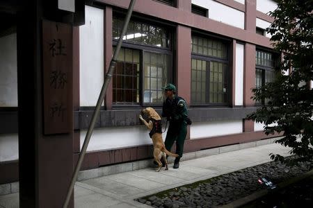 A police dog handler guides a dog as it searches for explosives after a blast at the Yasukuni shrine in Tokyo, Japan, November 23, 2015. REUTERS/Toru Hanai