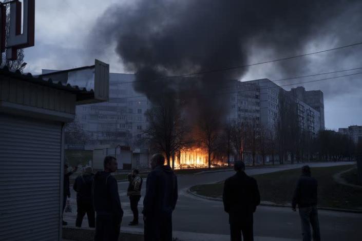 Los residentes permanecen fuera de sus apartamentos mientras las tiendas arden despu&#xe9;s de un ataque ruso en Kharkiv, Ucrania, el lunes 11 de abril de 2022.
