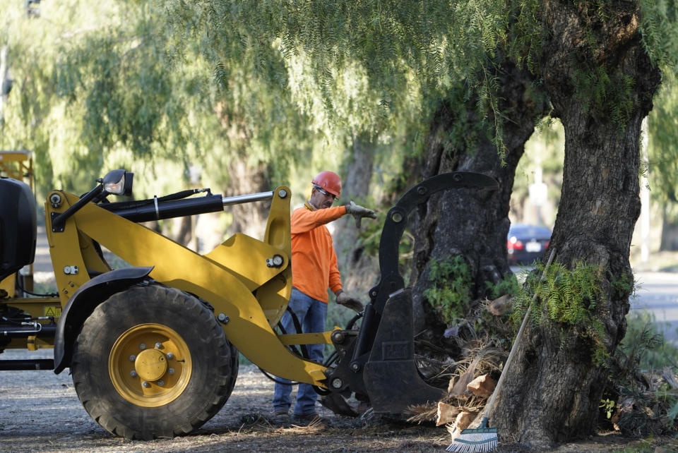 A crew removes tree debris after a windstorm in Upland, Calif., on Monday, Jan. 24, 2022. After estimating a loss in revenue in the early months of the pandemic in 2020, city officials say Upland is now doing well financially, boosted partly by federal pandemic aid. The city plans to use part of that aid for sidewalk and street repairs. (AP Photo/Damian Dovarganes)