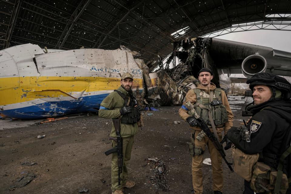 Ukrainian servicemen stand next to the destroyed Antonov An-225 Mriya aircraft.