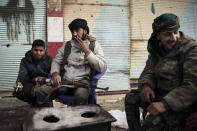 U.S.-backed Syrian Democratic Forces (SDF) fighters sit outside a building as fight against Islamic State militants continue in the village of Baghouz, Syria, Saturday, Feb. 16, 2019. (AP Photo/Felipe Dana)