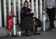 A woman takes her place as she waits to refill an oxygen tank for a family member sick with COVID-19 in the Iztapalapa district of Mexico City, Tuesday, Jan. 26, 2021. The city is offering free oxygen refills for COVID-19 patients. (AP Photo/Marco Ugarte)