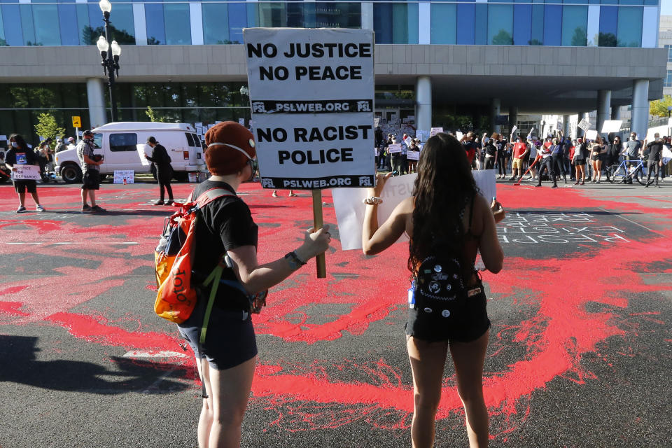 FILE - In this July 9, 2020, file photo, protesters gather in front of district attorney's office in Salt Lake City. Some Black Lives Matter protesters in Utah could face up to life in prison if they're convicted of splashing red paint and smashing windows during a protest, a potential punishment that stands out among demonstrators arrested around the country and one that critics say doesn't fit the alleged crime. (AP Photo/Rick Bowmer, File)