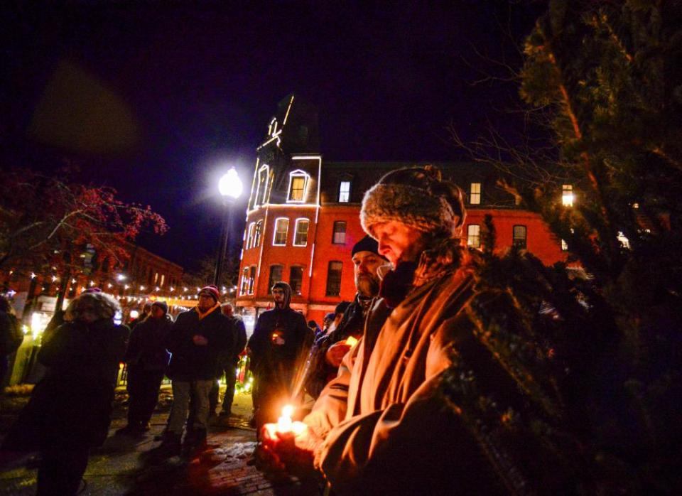 A nighttime photo of people dressed in winter clothes holding candles.