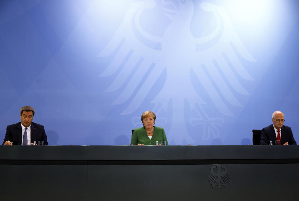 From left, Bavarian State Prime Minister Markus Soeder, German Chancellor Angela Merkel and Mayor of Hamburg Peter Tschentscher attend a news conference following a meeting with leaders of the 16 federal states to discuss the country's response following the spread of the coronavirus, at the Chancellery in Berlin, Thursday, Aug. 27, 2020. In an effort to harmonize different coronavirus measures across the country, Germany will implement a nationwide fine for people not wearing face masks and also ban mass events until the end of the year, Chancellor Angela Merkel said Thursday. (Michele Tantussi/Pool Photo via AP)