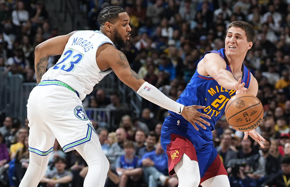 Denver Nuggets guard Collin Gillespie, right, passes the ball as Minnesota Timberwolves guard Monte Morris defends in the first half of an NBA basketball game Friday, March 29, 2024, in Denver. (AP Photo/David Zalubowski)