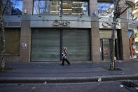 FILE - A woman passes a cosmetic shop that closed after the economy crisis in the commercial area in Beirut, Lebanon, Wednesday, Jan. 12, 2022. Some 1.6 billion people in 94 countries face at least one dimension of the crisis in food, energy and financial systems, according to a report last month by the Global Crisis Response Group of the United Nations Secretary-General. (AP Photo/Hussein Malla, File)