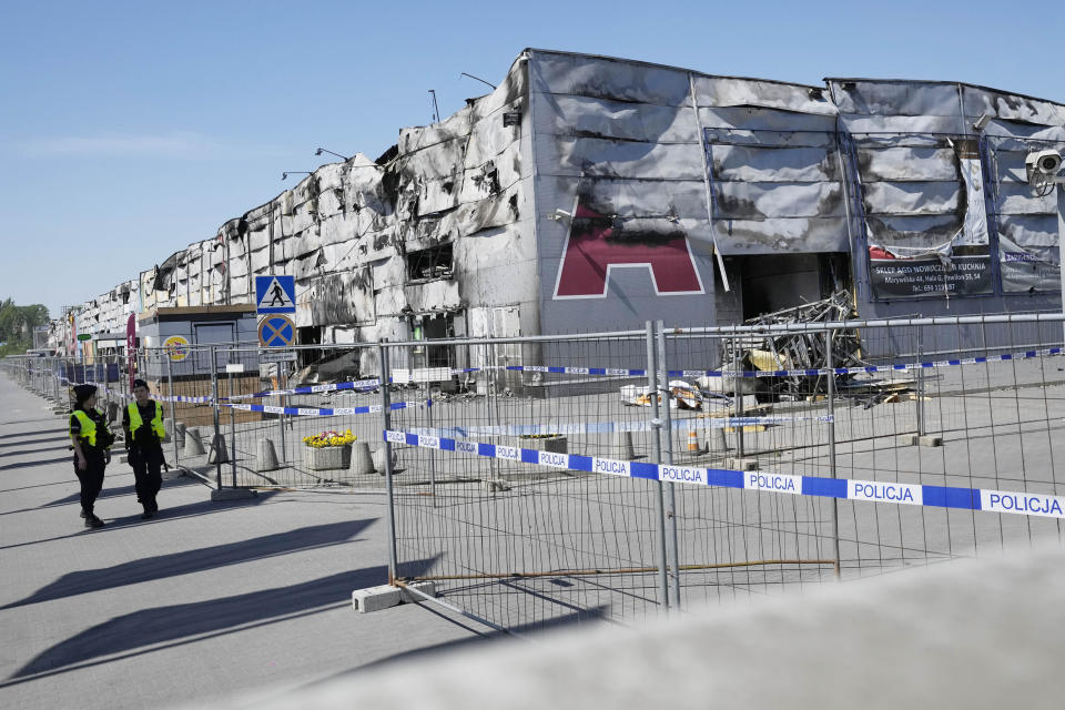 Police walks by a temporary fence put up to block access to a burnt-down shopping center in Warsaw, Poland, on Wednesday, May 15, 2024. A weekend fire at the Marywilska 44 shopping center dealt tragedy to many members of Poland's Vietnamese community. People lost entire livelihoods and say they don't know how they will manage to make a living. (AP Photo/Czarek Sokolowski)