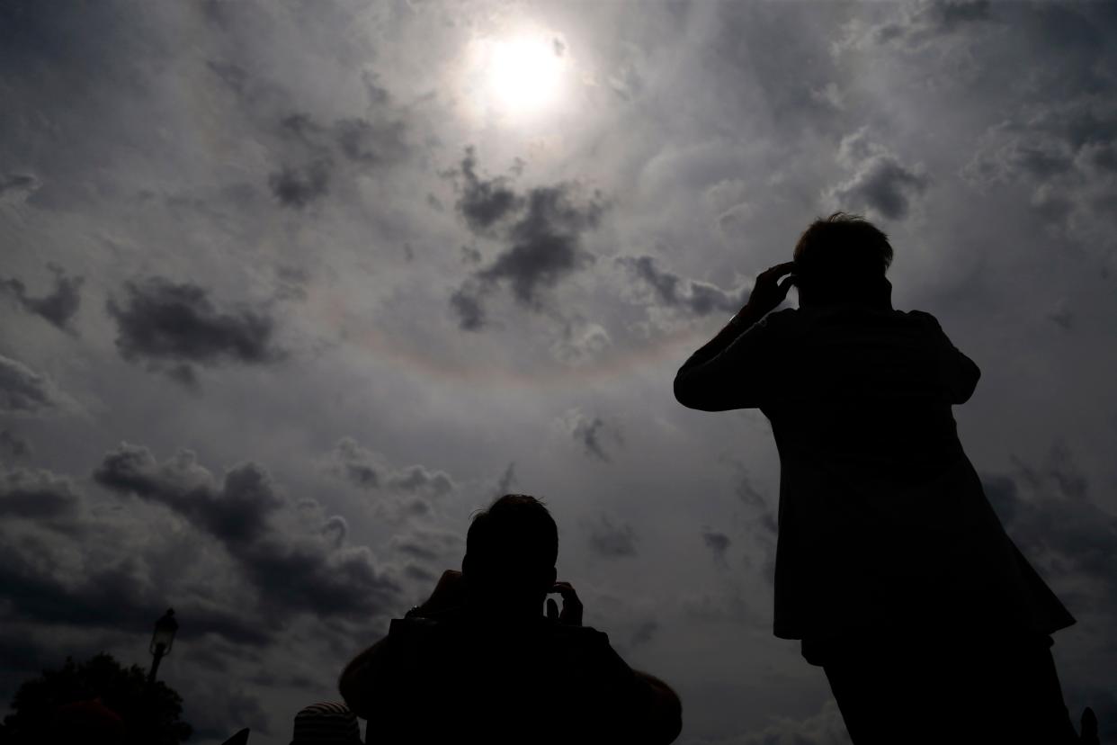 Eclipse watchers look up as the clouds break Monday, Aug. 21, 2017, during a solar eclipse watch party outside the Iowa State Capitol in Des Moines.