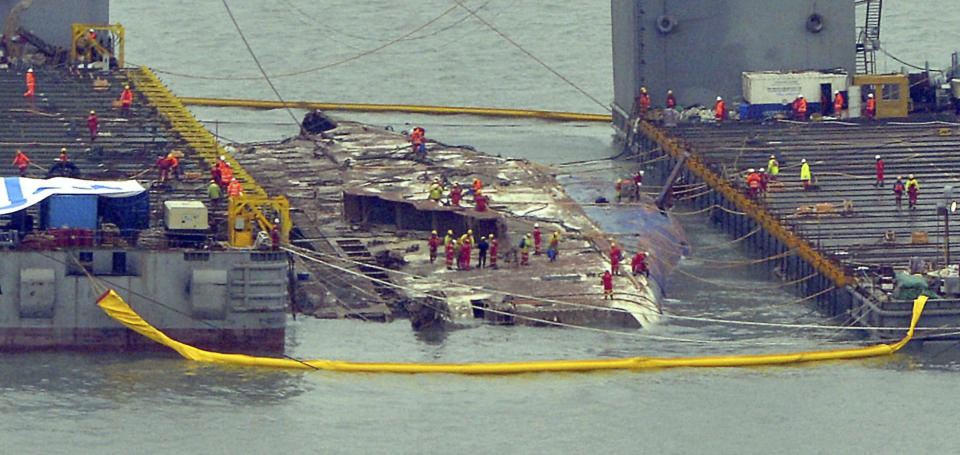 Workers prepare to lift the sunken Sewol ferry, center, in waters off Jindo, South Korea, Thursday, March 23, 2017. A 6,800-ton South Korean ferry emerged from the water on Thursday, nearly three years after it capsized and sank into violent seas off the country's southwestern coast, an emotional moment for the country that continues to search for closure to one of its deadliest disasters ever. (Park Gyung-woo/Hankookilbo via AP)