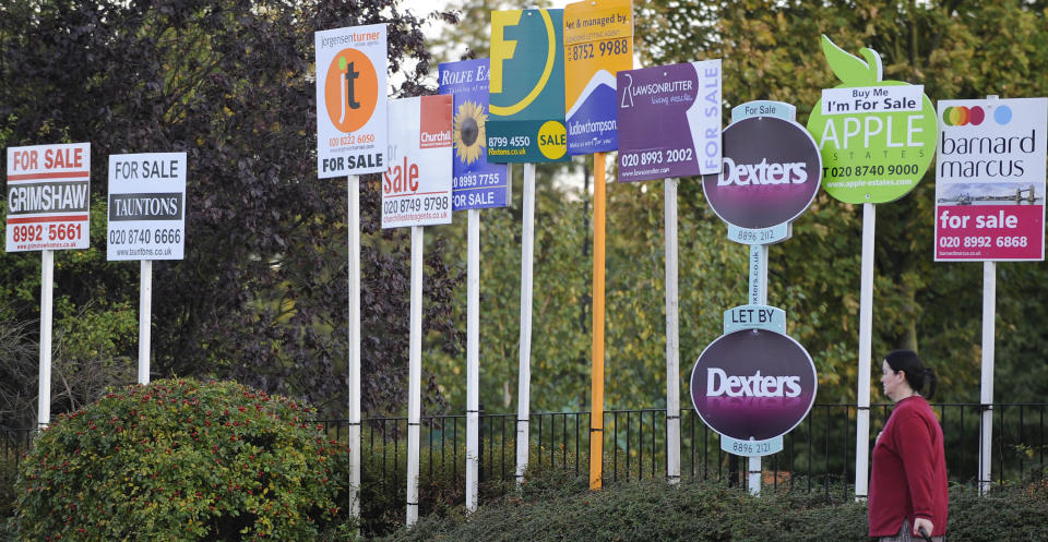 A woman passes property signs, in west London. Photo: Toby Melville/Reuters