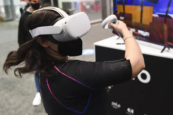 An attendee demonstrates the Owo vest, which allows users to feel physical sensations during metaverse experiences such as virtual reality games, including wind, gunfire or punching, at the Consumer Electronics Show (CES) on January 5, 2022 in Las Vegas, Nevada. - The CES tech show threw open its doors Wednesday in Las Vegas despite surging Covid-19 cases in the United States, as one of the world&#39;s largest trade fairs tried to get back to business.
Despite some obvious gaps on the showfloor -- after high-profile companies like Amazon and Google cancelled over climbing virus risk -- crowds of badge-wearing tech entrepreneurs, reporters and aficionados poured through venues. (Photo by Patrick T. FALLON / AFP) (Photo by PATRICK T. FALLON/AFP via Getty Images)