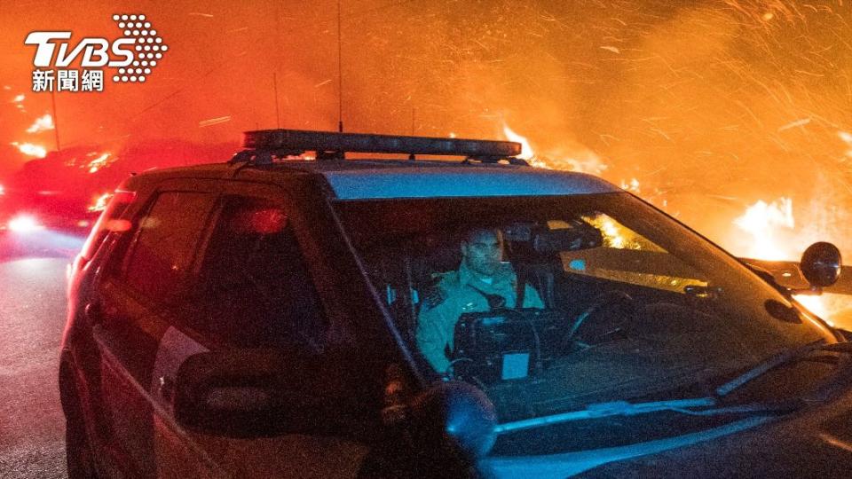 一名公路警察行駛在一號公路上，公路旁燃起熊熊大火。（圖／達志影像美聯社）
