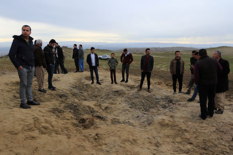 Residents look at a crater caused by a missile launched by Iran on U.S.-led coalition forces on the outskirts of Duhok