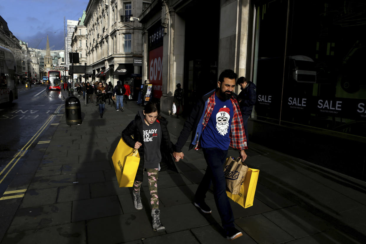 People with shopping bags walk on Oxford street in a last day before Christmas in central London, England, Tuesday, Dec. 24, 2019. (AP Photo/Petros Karadjias)