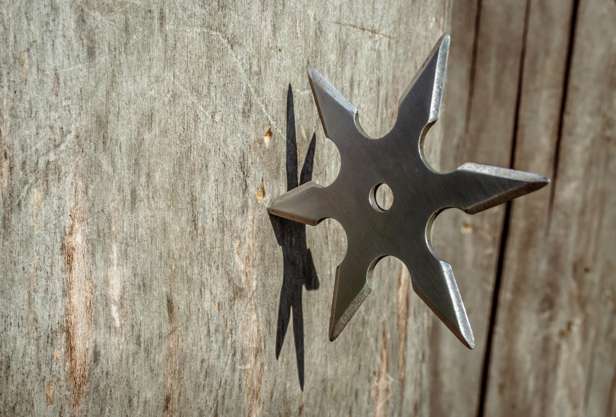 Shuriken (throwing star), traditional japanese ninja cold weapon stuck in wooden background