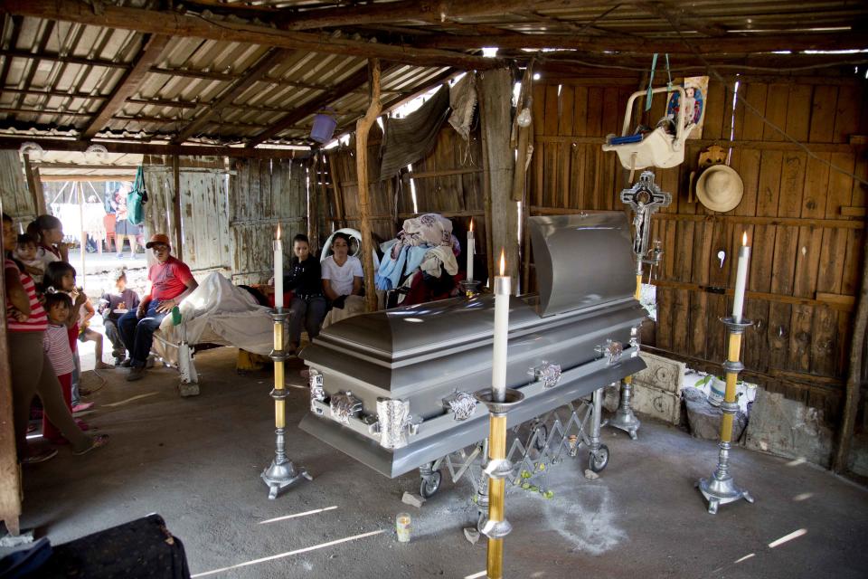 CORRECTS TO REMOVE THE WORD CROSSFIRE AND CLARIFY ALLEGED CIRCUMSTANCES - Relatives stand next to the coffin of Mario Perez, 50, killed during recent violence in Antunez, Mexico, Tuesday, Jan. 14, 2014. The Mexican government moved in to quell violence between vigilantes and a drug cartel, and witnesses say several unarmed civilians were killed in an early Tuesday confrontation. According to family members at the funeral, Perez died after soldiers opened fire on self-defense vigilantes and their supporters, after the crowd surrounded a military convoy and refused to let their vehicles proceed, amid fears the military was going to try to disarm the self-defense forces. (AP Photo/Eduardo Verdugo)