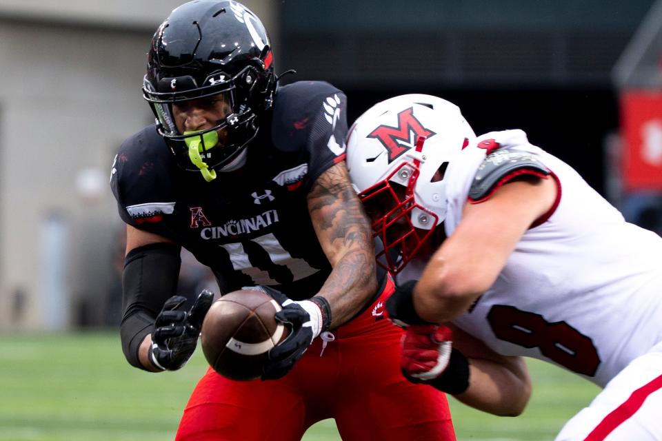 Cincinnati Bearcats tight end Leonard Taylor (11) scores a touchdown as Miami Redhawks linebacker Luke Bolden (8) hits him in the second half of the NCAA football game on Saturday, Sept. 4, 2021, at Nippert Stadium in Cincinnati. Cincinnati Bearcats defeated Miami Redhawks 49-14. 