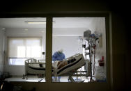 FILE - In this July 14, 2020 file photo, Dr. Adriana Coronel attends a COVID-19 patient at the Eurnekian Ezeiza Hospital on the outskirts of Buenos Aires, Argentina during a government-ordered lockdown to curb the spread of the new coronavirus. People are on edge in Argentina, where the number of new coronavirus cases is surging despite nearly five months of strict limits on movement and activities in Buenos Aires and the surrounding area. (AP Photo/Natacha Pisarenko, File)