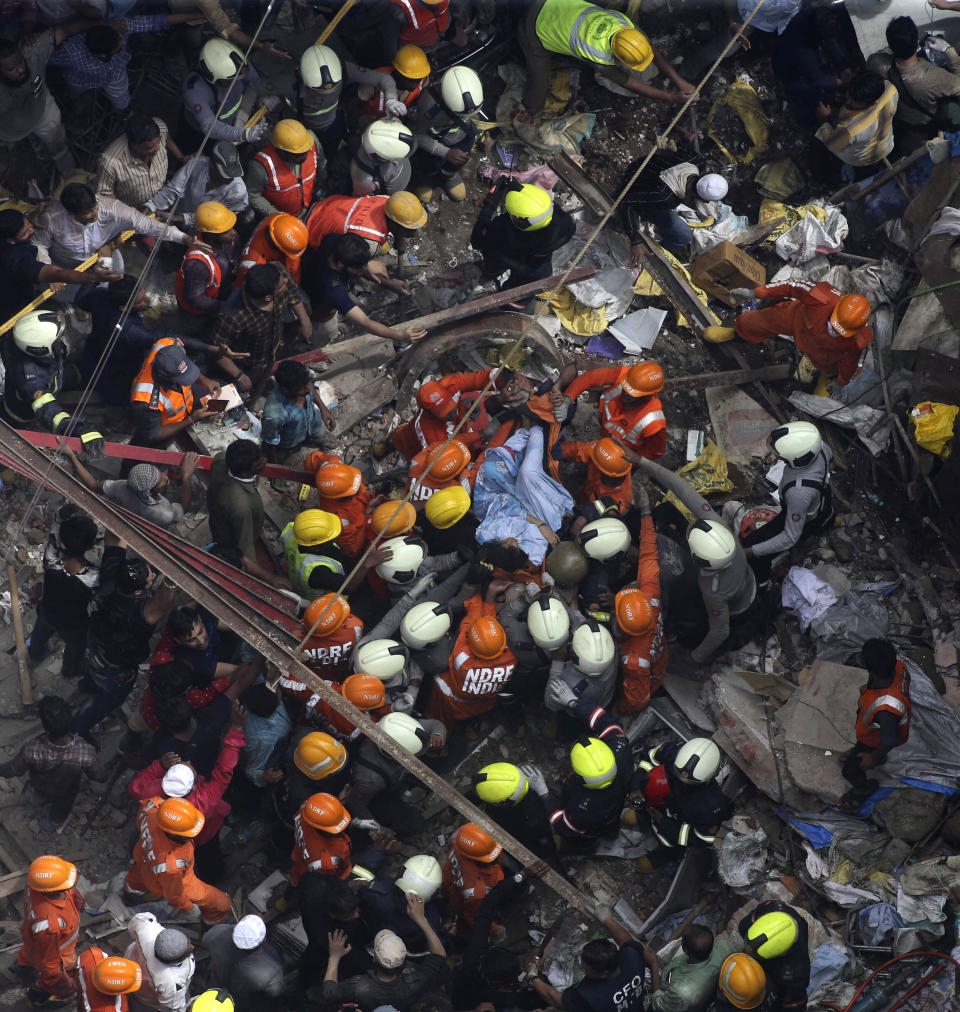 Rescuers carry out a survivor from the site of a building that collapsed in Mumbai, India, Tuesday, July 16, 2019. A four-story residential building collapsed Tuesday in a crowded neighborhood in Mumbai, India's financial and entertainment capital, and several people were feared trapped in the rubble, an official said. (AP Photo/Rajanish Kakade)