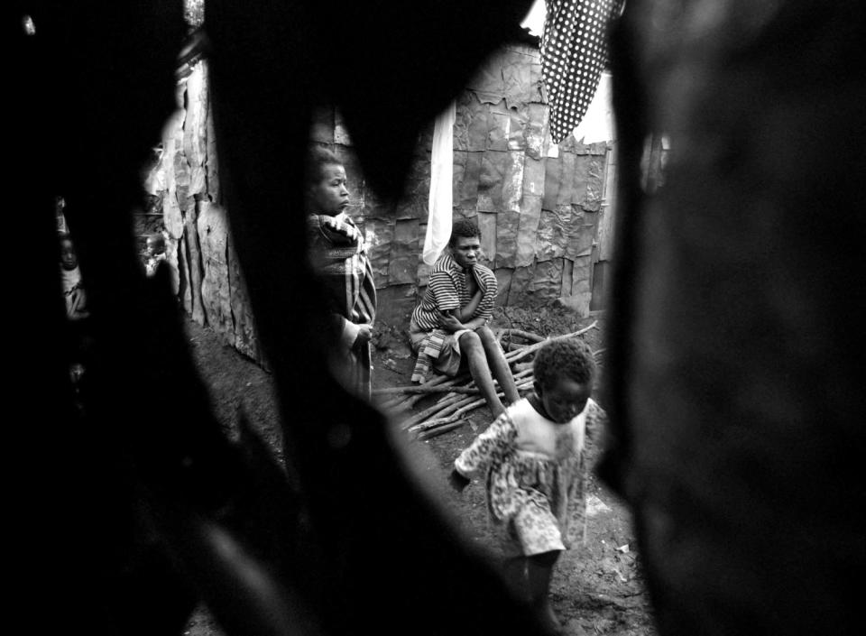 Peeking through holes in the Cecilia Wahu's tin house, Wairimu Wahu and Margaret Wambui are visible