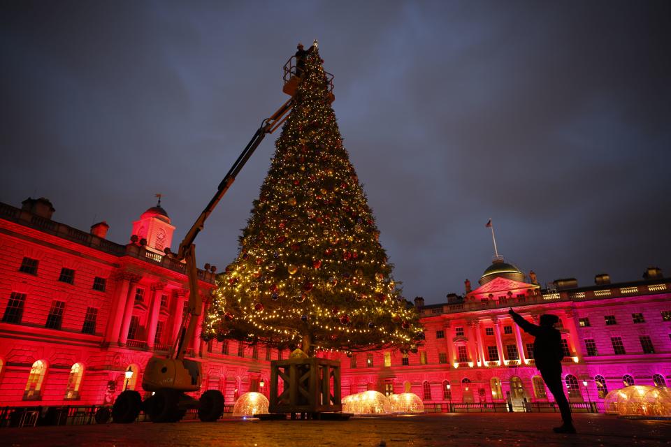 A contractor uses a cherrypicker to place final decorations on a 40ft Christmas tree during a photo call in the courtyard of Somerset House in London on December 3, 2020. (Photo by Tolga Akmen / AFP) (Photo by TOLGA AKMEN/AFP via Getty Images)