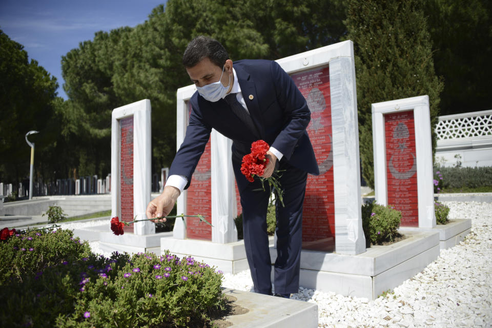 In this Friday, April 24, 2020, photo provided by the Canakkale Governorate, Canakkale Governor Orhan Tavli places carnations on the graves of fallen Turkish soldiers at Turkish cemetery during the commemoration ceremonies marking 105th anniversary of the Gallipoli Campaign, in Canakkale, Turkey. Traditional mass celebrations on the ANZAC Day by Turks, Australians, New Zealanders, British and French have been cancelled due to new coronavirus outbreak this year. (Kadir Oztecik/Canakkale Governorate via AP)