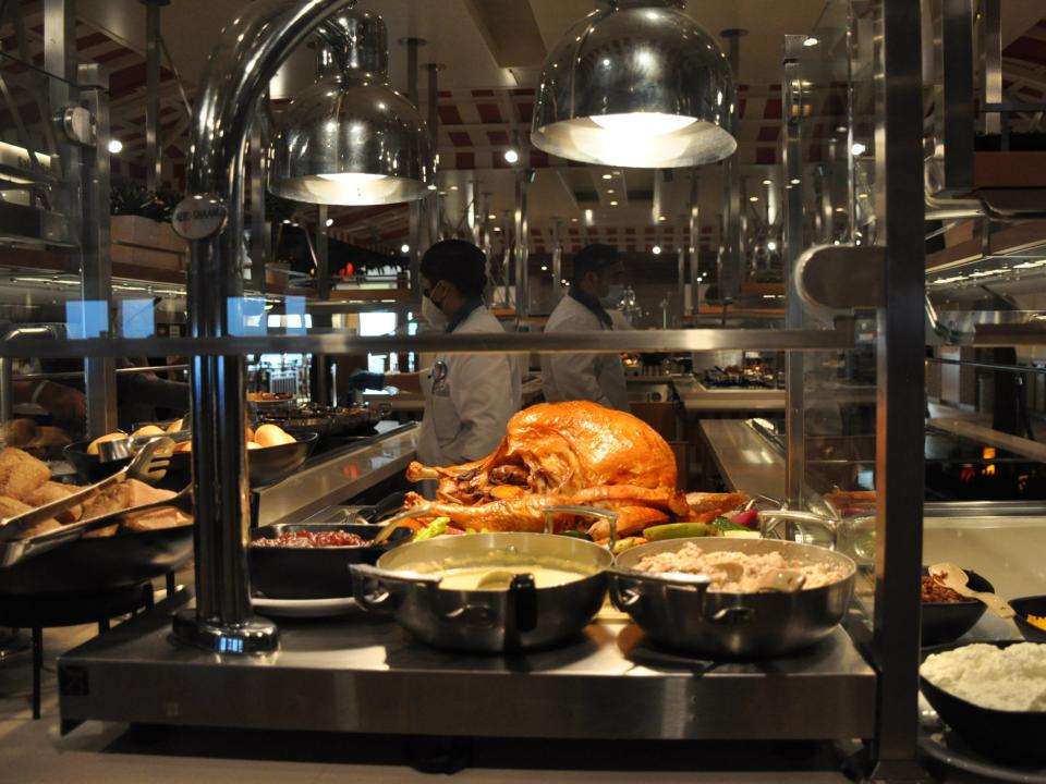 A view of an open kitchen area with a buffet in front and a roasted turkey.