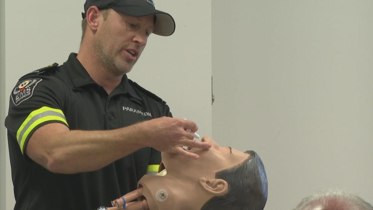 A member of the Essex Windsor MES team demonstrates how to use a naloxone kit at a community event on opioid overdose prevention on Wednesday. (Jennifer La Grassa/CBC - image credit)