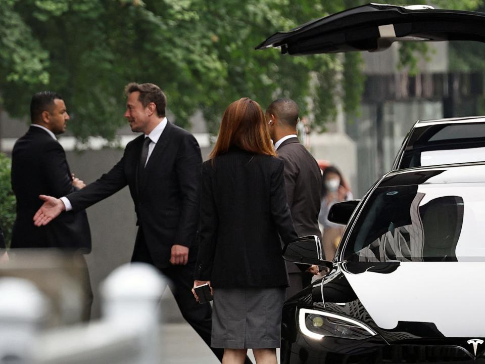 Elon Musk reaches out for a handshake before leaving the Chinese Ministry of Commerce in Beijing