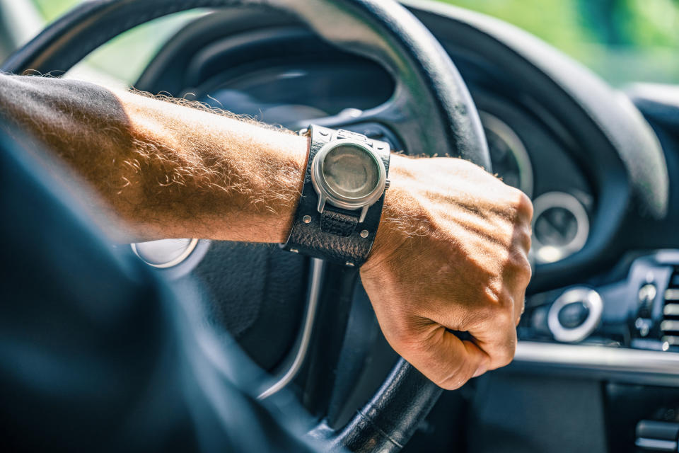 one hand on a steering wheel