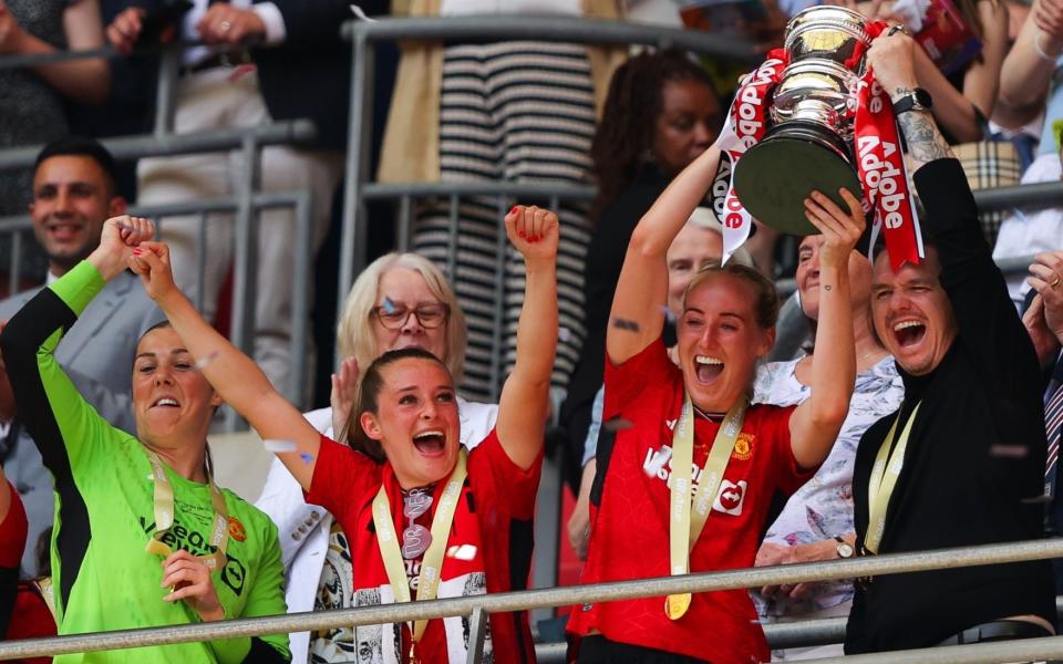 Marc Skinner, manager of Manchester United Women, lifts the Women's FA Cup with his players