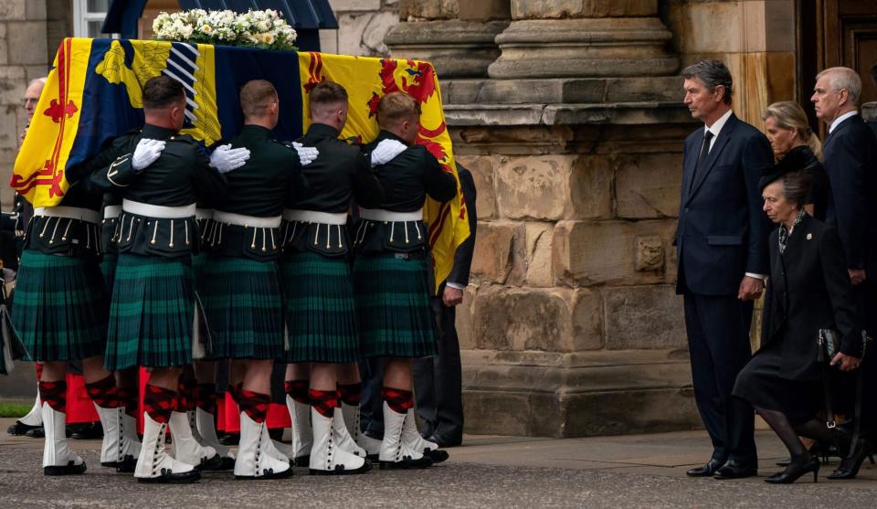 TOPSHOT - Vice Admiral Timothy Laurence (4R), Britain's Sophie, Countess of Wessex (2R) and Britain's Prince Andrew, Duke of York (R) stands as Britain's Princess Anne, the Princess Royal curtseys to the coffin of Queen Elizabeth II, draped with the Royal Standard of Scotland, as it is carried in to the Palace of Holyroodhouse, in Edinburgh on September 11, 2022. - The coffin carrying the body of Queen Elizabeth II left her beloved Balmoral Castle on Sunday, beginning a six-hour journey to the Scottish capital of Edinburgh. (Photo by Aaron Chown / POOL / AFP) (Photo by AARON CHOWN/POOL/AFP via Getty Images)