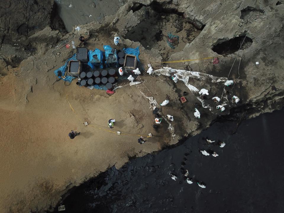 Aerial view of cleaning crews working to remove oil from a beach annexed to the summer resort town of Ancon, northern Lima, on January 22, 2022 after a spill which occurred during the offloading process of the Italian-flagged tanker 