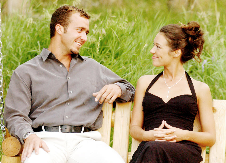 a man and woman sit on a bench and look at each other