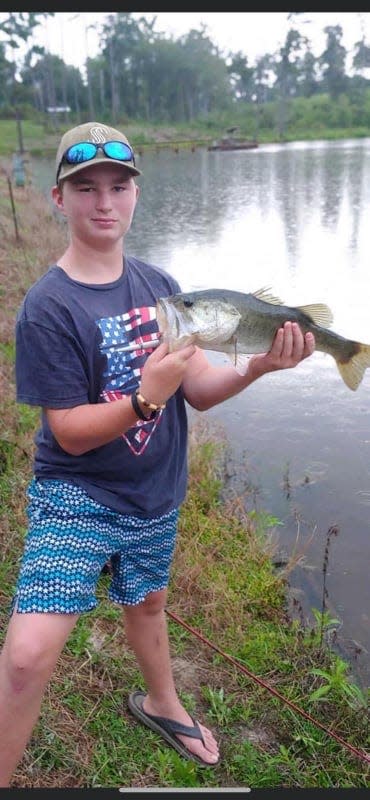 Grayson Gunn holds up a fish he caught to the camera.