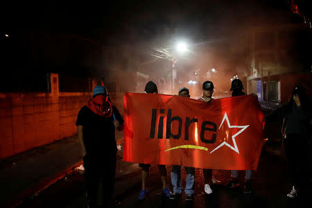 Supporters of Salvador Nasralla, presidential candidate for the Opposition Alliance Against the Dictatorship, hold a flag in front of a barricade during a curfew while the country is still mired in chaos over a contested presidential election in Tegucigalpa, Honduras December 3, 2017. REUTERS/Edgard Garrido