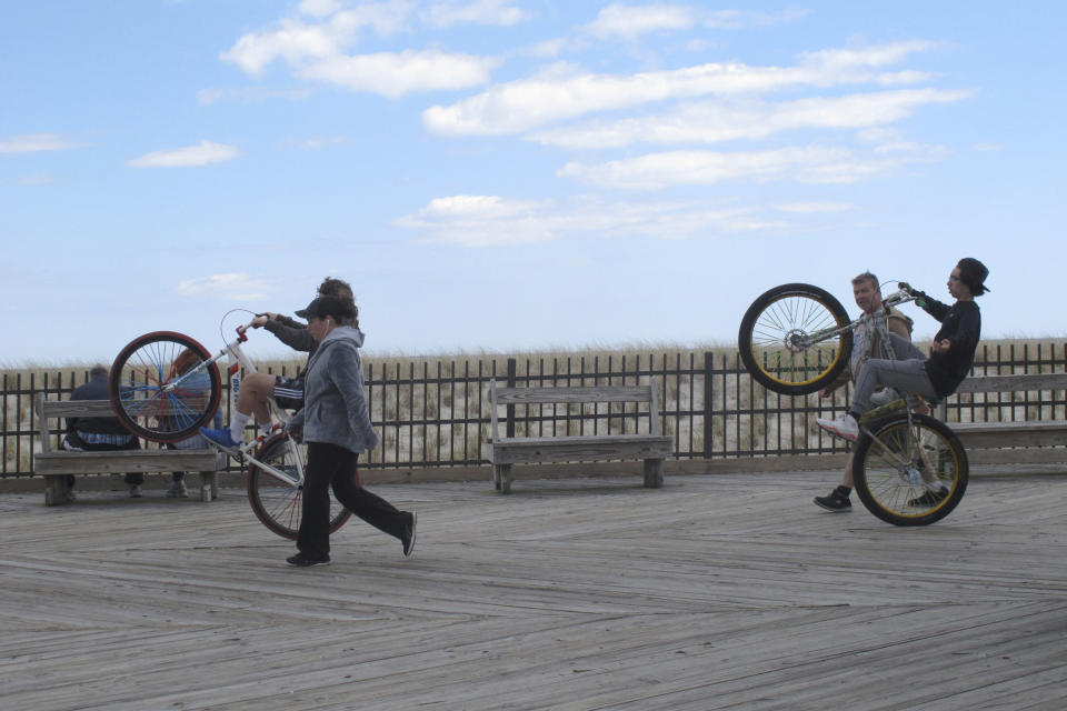 Bicycle riders do wheelies on the Seaside Heights N.J. boardwalk on April 18, 2021. On Feb. 23, 2024, New Jersey selected 18 Jersey Shore towns to split $100 million in funds to repair or rebuild their boardwalks. (AP Photo/Wayne Parry)