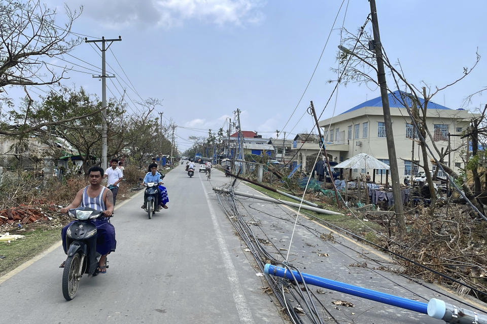 Local people ride motorbike with lamp-posts fallen on a roadside after Cyclone Mocha in Sittwe township, Rakhine State, Myanmar, Friday, May 19, 2023. Cyclone Mocha roared in from the Bay of Bengal on Sunday with high winds and rain slamming a corner of neighboring Bangladesh and a wider swath of western Myanmar's Rakhine state. (AP Photo)