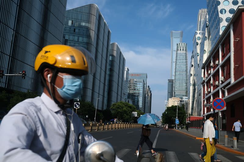 A Meituan delivery worker wearing a face mask crosses a street, following the coronavirus disease (COVID-19) outbreak, in Beijing's central business area