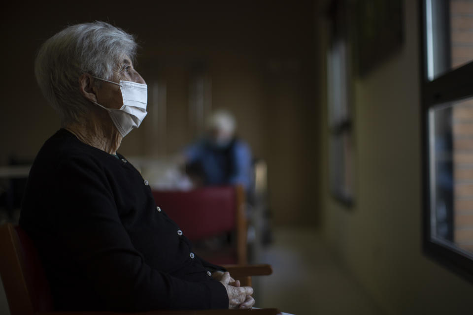 A resident wearing a face mask to protect against the spread of coronavirus looks on though a window at DomusVi nursing home in Leganes, Spain, Wednesday, March 10, 2021. (AP Photo/Manu Fernandez)