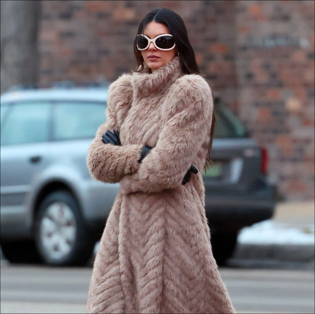  Kendall Jenner wearing a fur coat and a pair of white bug eye sunglasses. 