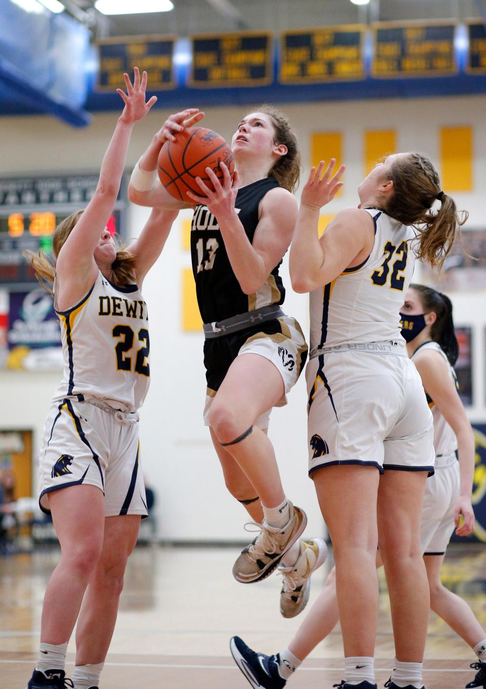 Holt's Claire Groenewoud, center, goes to the basket between DeWitt's Madison Uyl, left, and Morgan Bethard, right, Tuesday, Jan. 18, 2022, in DeWitt, Mich. Holt won 49-48.