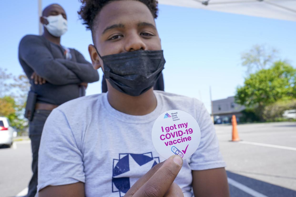 Wilmer Moro, left, watches as his son Wilmer Moro, 13, poses for a photo with his vaccination sticker after being inoculated with the first dose of the Pfizer COVID-19 vaccine at the Mount Sinai South Nassau Vaxmobile parked at the De La Salle School, Friday, May 14, in Freeport, N.Y. 