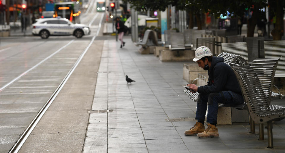 A construction worker is seen sitting on a bench along Bourke Street in Melbourne, Friday, July 23, 2021.