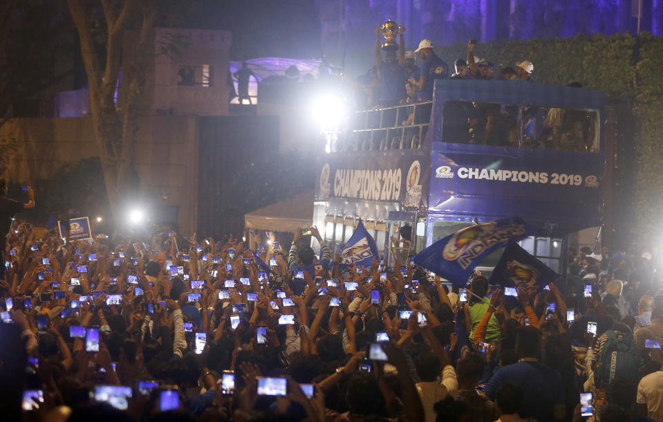 Mumbai Indians team members stand in a bus as people capture the moment in their mobile phones during a reception accorded to them in Mumbai, India, Monday, May 13, 2019. Mumbai Indians won the Indian Premier League 2019 cricket title on Sunday defeating Chennai Super Kings by one run. (AP Photo/Rafiq Maqbool)