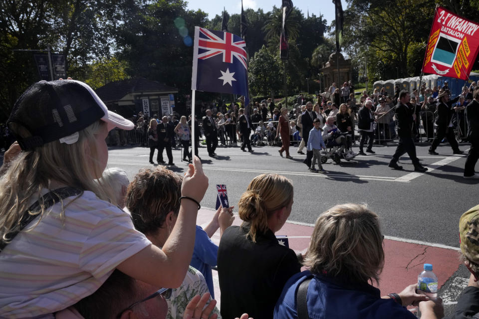 A young girl, left, waves an Australian flag as she watches the Anzac Day parade in Sydney, Tuesday, April 25, 2023. (AP Photo/Rick Rycroft)