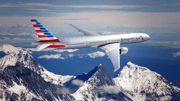 An American Airlines plane in flight, with mountains in the background