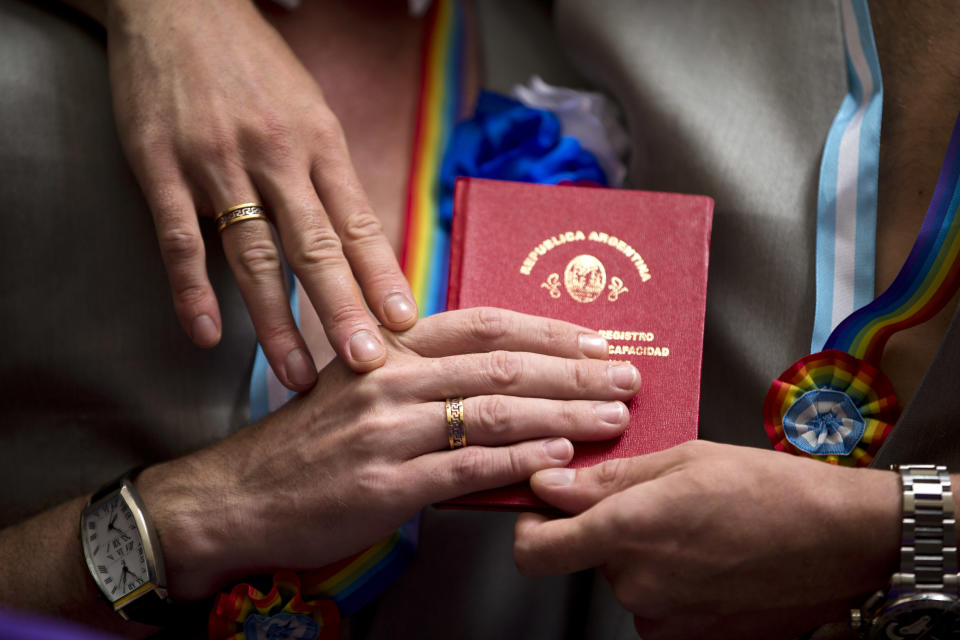Wearing their marriage rings, newlyweds Alexander Emereev and Dmitry Zaytsev, both of Russia, hold their marriage book in Buenos Aires, Argentina, Tuesday, Feb. 25, 2014. The two men who are from Sochi planned to apply for political asylum from Russia after their marriage ceremony at the civil registry. (AP Photo/Victor R. Caivano)