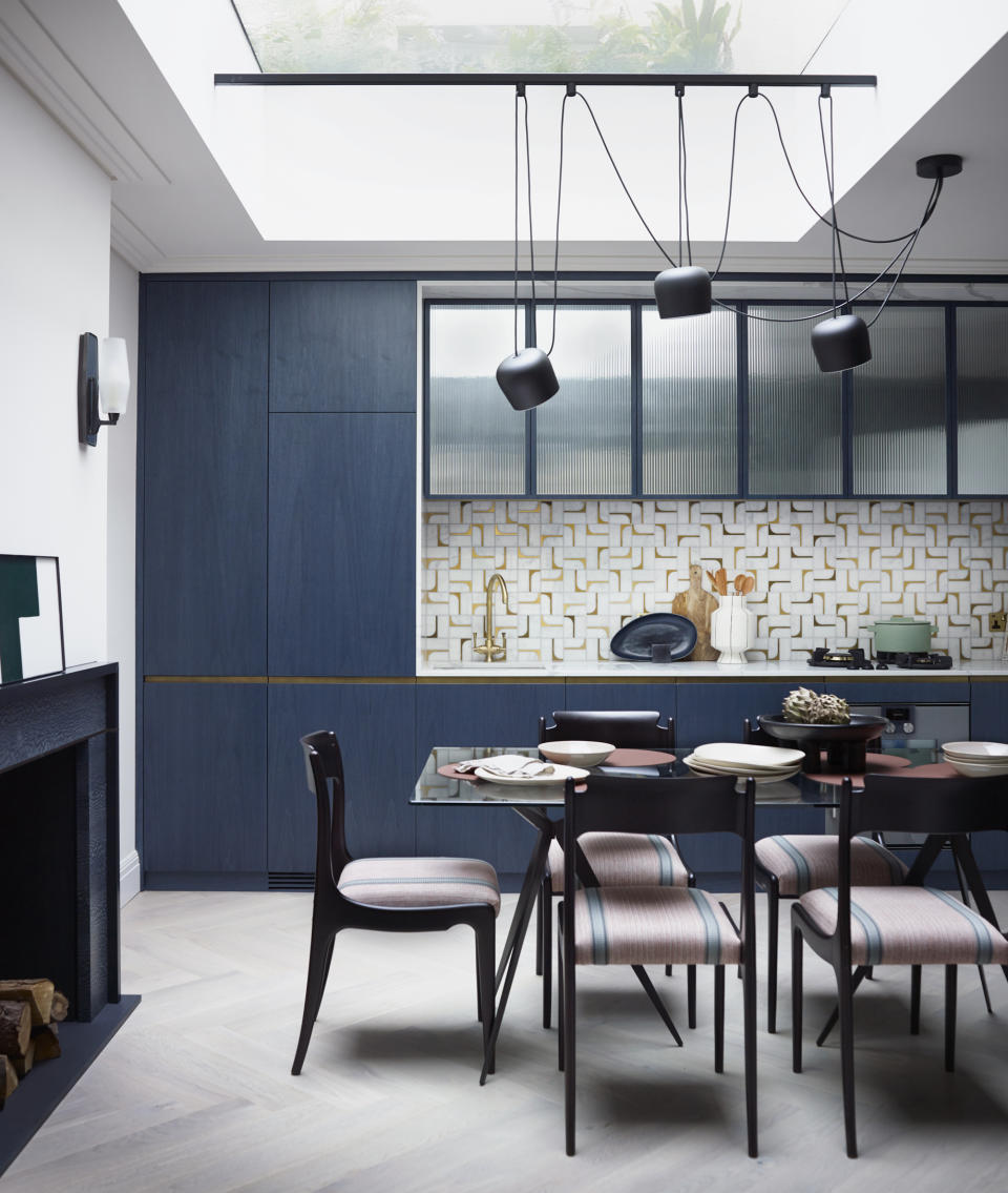 blue modern kitchen with black table and chairs and black hanging pendant lights